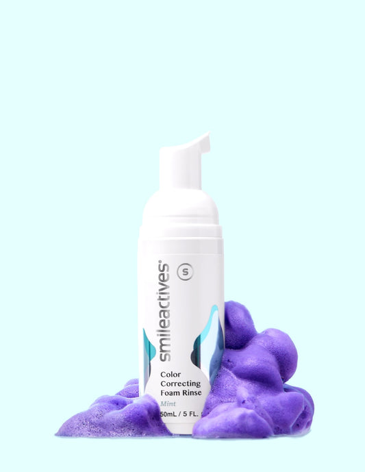 Smile Actives color correcting foam rinse bottle with purple foam on a light blue background